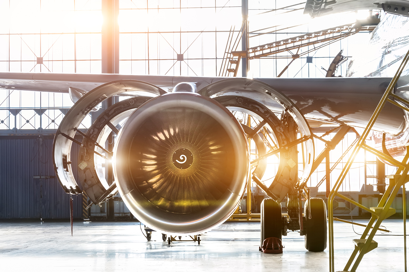 Opened hood airplane engine jet under maintenance in the hangar ,with bright light flare at the gate